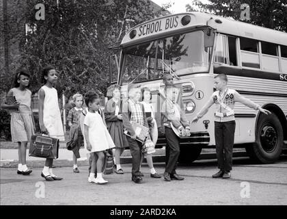 1960ER-JAHRE GRUPPE VERSCHIEDENER SCHÜLER, DIE DIE STRASSE VOR DEM SCHULBUS MIT PATROUILLENJUNGEN DURCHQUEREN, DIE DEN VERKEHR HALTEN - S14762 HAR001 HARS B&W-SCHULEN SCHULSCHUTZ AFRIKANAMERIKANER AFRIKANISCHAMERIKANER SCHWACHES SCHWARZES ETHNIZITÄTS-GRUNDPATROUILLE SCHULKINDER VERSCHIEDENE K-12-SCHULKLASSEN MIT VARIIERTER ZUSAMMENARBEIT JUGENDLICHE VOR TEENAGER MÄDCHEN VOR TEENAGER, DIE SICH ZUSAMMENFINDEN, SCHWARZ UND WEISSE KAUKASISCHE ETHNIE HAR001 ALTMODISCHE AFROAMERIKANISCHE AMERIKANER Stockfoto