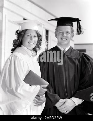 1970ER JAHRE PORTRAIT LÄCHELNDES TEENAGER-STUDENTPAAR IN ABSCHLUSSGEWÄNDERN MIT BLICK AUF DIE KAMERA - S19132 HAR001 HARS PAAR ROMANCE BEAUTY SUBURBAN SENIORS EXPRESSION OLD TIME GRADUATE NOSTALGIE OLD FASHION 1 JUGENDLICHE GESICHTSBEHANDLUNG JUNGE ERWACHSENE TEAMARBEIT FREUT SICH FREUDE LIFESTYLE ZUFRIEDENHEIT FEIER FRAUEN KOPIEREN RAUM FREUNDSCHAFT HALBE LÄNGE JUGENDLICHE PERSONEN MÄNNER TEENAGER MÄDCHEN TEENAGER, DER SELBSTBEWUSSTSEIN STUDIERT, AUSDRÜCKE ABSOLVENTEN B&W AUGENKONTAKT ZIELE ERFOLG TRÄUME GLÜCK FRÖHLICHE GEWÄNDER STÄRKE SIEG UNIVERSITÄTEN WISSEN FORTSCHRITT RICHTUNG STOLZ AUF DIE HIGHSCHOOL LÄCHELT HIGH SCHOOLS HOCHSCHULBILDUNG Stockfoto