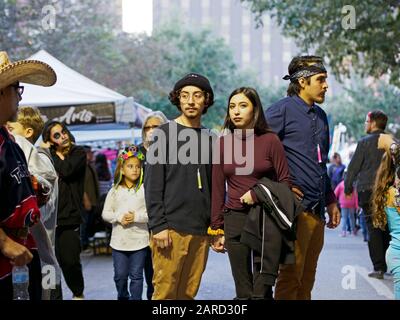 Ein junges Paar hält während der Dia De Los Muertos Feier 2019 die Hände in der Innenstadt von Corpus Christi, Texas USA. Stockfoto