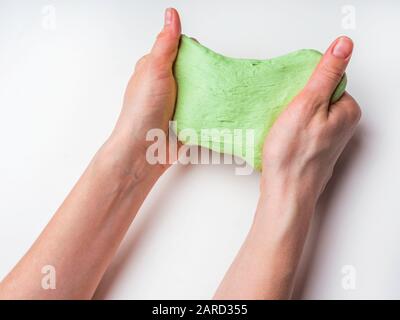 Klebriger Schleim in der Hand. Der grüne Schleim in den Händen. Lieblingsspielzeug für ein Kind. Hobby, angenehm für den Antistress-Trainer Stockfoto