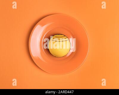Gelber runder Kuchen auf dem orangefarbenen Tisch. Draufsicht Stockfoto