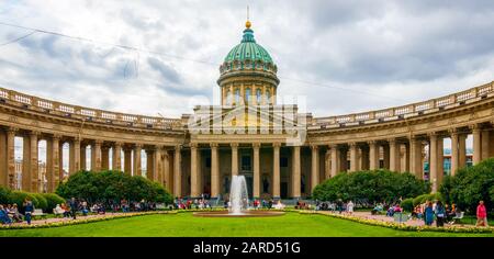 Panoramablick auf die Kazanskij Kafedralniy Sobor (Kasaner Kathedrale) und unidentifizierte Menschen im Park unter einem bewölkten Himmel. Sankt Petersburg, Russland. Stockfoto