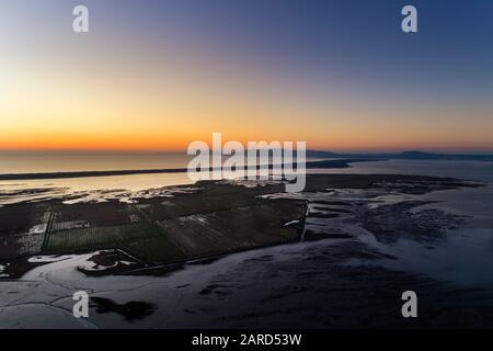 Luftaufnahme der Sado Estuary in der Nähe des Dorfes Carrasqueira, mit einer Reisplantage, der Troia Halbinsel und dem Arrabida Berg auf dem Rücken Stockfoto