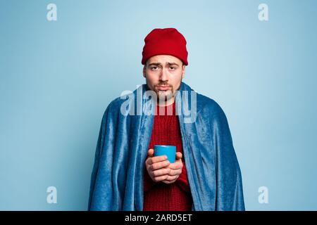 Der Junge hat eine Erkältung erwischt und trinkt heiß. Hintergrund Zyan. Konzept der Krankheit Stockfoto