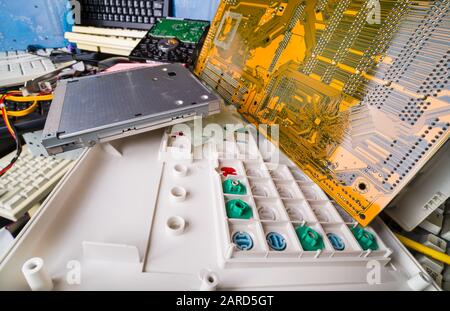 Zerlegte Computerhardteile. E-Waste Pfahldetails. Farbige Gummikuppelschalter auf der Tastatur. Leiterplatte auf Mainboard, Laptop-CD-Laufwerk, PC-Festplatte. Stockfoto