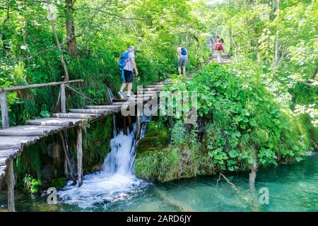 Touristen erkunden die Holzstege im Nationalpark Plitvicer Seen in Kroatien Stockfoto