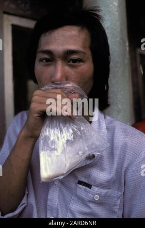 JUNGER MANN IN SINGAPUR LEIMSCHNÜFFELN. AUCH BEKANNT ALS BAGGING, GLADING, DUSTING ODER HUFFING. Stockfoto