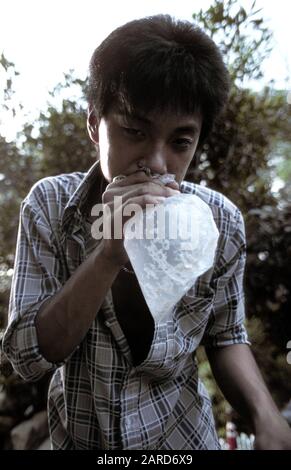 JUNGER MANN IN SINGAPUR LEIMSCHNÜFFELN. AUCH BEKANNT ALS BAGGING, GLADING, DUSTING ODER HUFFING. Stockfoto