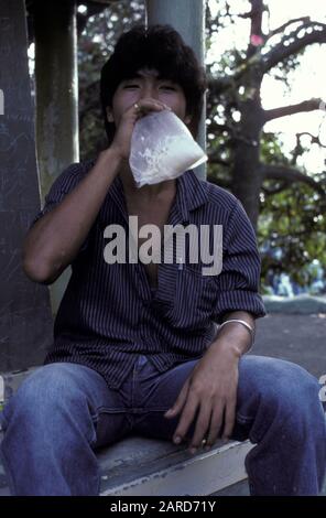 JUNGER MANN IN SINGAPUR LEIMSCHNÜFFELN. AUCH BEKANNT ALS BAGGING, GLADING, DUSTING ODER HUFFING. Stockfoto