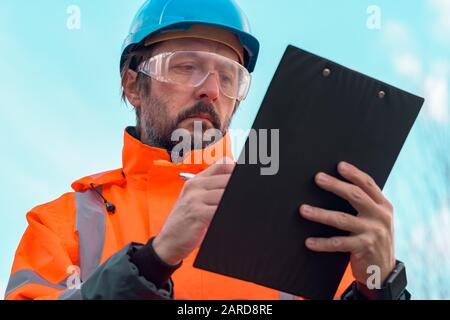 Forsttechniker sammelt Daten in Wald und schreibt Notizen auf Notizblock in der Zwischenablage Stockfoto