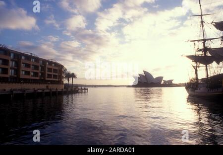 BLICK AM FRÜHEN MORGEN AUF DIE OPER VON SYDNEY MIT NACHBILDUNG DER KOPFGELDUNTERUNG AUF DER RECHTEN SEITE UND DEM PARK HYATT HOTEL AUF DER LINKEN SEITE, SYDNEY, NSW, AUSTRALIEN. Stockfoto
