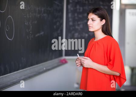 Hübsche, junge College-Student schreibt an die Tafel/Tafel während einer Math-Klasse Stockfoto