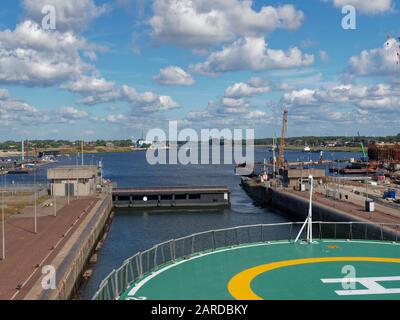 Die Öffnung der Schleuse Gates und ein Schiff, das sich darauf vorbereitet, die Schleuse zu verlassen und seine Fahrt zum Hafen von Amsterdam über den Nordseekanal fortzusetzen. Stockfoto