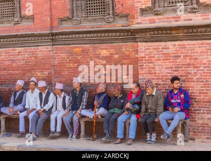 Männer, die auf einer Bank auf dem Durbar Platz in Patan, Nepal sitzen und entspannen Stockfoto