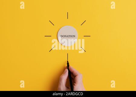 Wortspende, die auf einem Holzschnittkreis mit männlichen Handstrahlen in einem konzeptuellen Bild um sie herum geschrieben wurde. Stockfoto