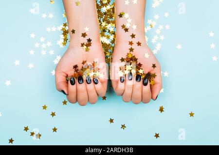 Hände mit schwarzen Maniküre und Goldene Sterne. Flach Stil. Stockfoto