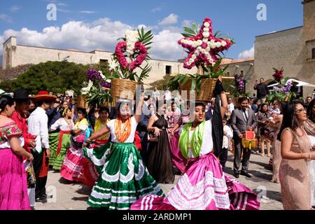 Frau tanzt in fließendem traditionellen Outfit mit Blumenkorb Teil der Traditionellen Hochzeitsfeier (Calenda de Bodas) auf den Straßen von Oaxaca. Stockfoto
