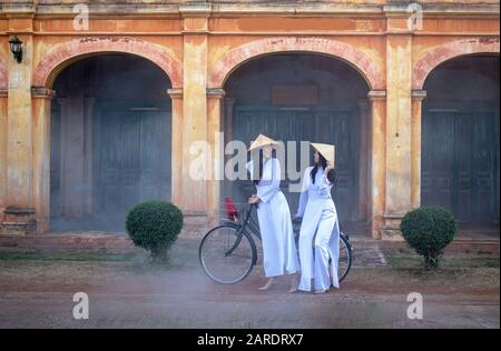 Zwei Frauen, die das traditionelle Kleid Ao Dai Vietnam tragen, übernachten im alten Dorf Stockfoto