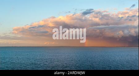 Panoramabild eines starken Regensturms und Wolken über der Küste Dänemarks mit einem Regenbogen über der Ostsee in Nordeuropa. Stockfoto