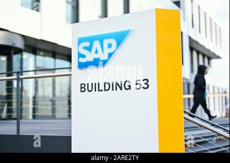 Walldorf, Deutschland. Januar 2020. Eine Frau läuft auf dem Gelände des Softwareunternehmens SAP hinter einer Tafel mit dem Firmenlogo. Am Dienstag (28. Januar) wird SAP seine Finanzergebnisse für das gerade abgeschlossene Jahr bekannt geben. Credit: Uwe Anspach / dpa / Alamy Live News Stockfoto