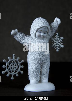 Vertikale Aufnahme einer niedlichen Baby-Statuette mit Schneeflocken Stockfoto