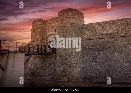 Blick auf den Sonnenuntergang über dem restaurierten Tor mit schützenden halbrunden Türmen von Chinchilla de Montearagon in der Nähe von Albacete Spanien Stockfoto