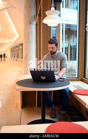 Rheinstetten, Deutschland. Januar 2020. Philipp Hassinger, Mitarbeiter der Karlsruher Drogerie dm, arbeitet im öffentlichen Bereich der Unternehmenszentrale, die "Dialogium" genannt wird. Die Bildungsmesse Learnedec, die am 28.01.2020 beginnt, befasst sich auch in diesem Jahr mit dem Vormarsch der "neuen Arbeit". Damit verstehen Unternehmen, ihren Mitarbeitern in der digitalen Welt veränderte räumliche, technische und zeitliche Bedingungen anzubieten, so dass DM räumlich ein offenes Konzept umgesetzt hat. Credit: Uli Deck / dpa / Alamy Live News Stockfoto