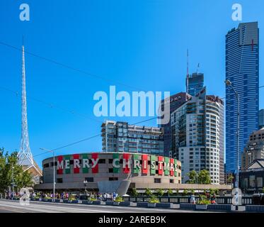 Melbourne, Australien - Ca. Dezember 2019: Arts Centre Exterieur mit fröhlichem Weihnachtstext an hellem sonnigen Tag mit Menschen, die auf Saint gehen Stockfoto