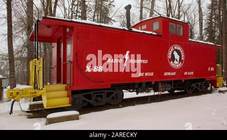 Eine leuchtend rote Caboose Der Great Northern Railway mit einem "Rocky Mountain Goat"-Logo auf der Seite, geparkt auf einer abgetrennten Schiene, in der Nähe von Callahan Creek, in Troy Stockfoto