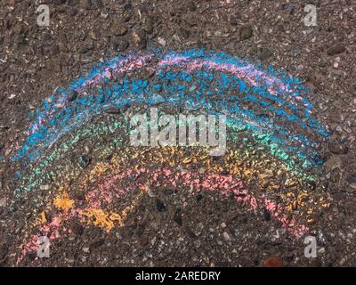 Regenbogen mit Kelchen auf der Asphaltoberfläche gezeichnet. Stockfoto