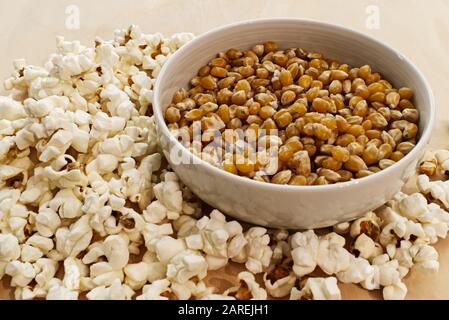 Popcorn und Mais in einer weißen Schüssel auf Holztisch Stockfoto