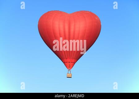 Valentinstag. Das rote Herz am blauen Himmel. Flug auf einem Heißluftballon in Form des Herzens, Symbol der Liebe Stockfoto