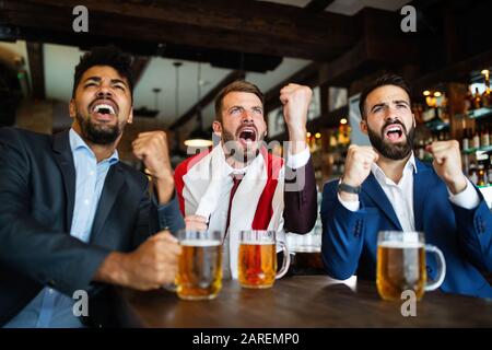 Menschen, Freizeit, Freundschaft, Sportkonzept. Fröhliche Freunde, die Bier trinken, beim Sportspiel in der Kneipe zusehen Stockfoto