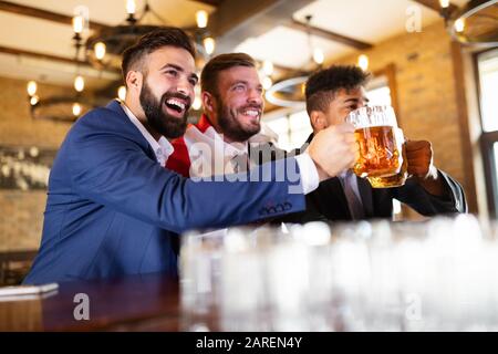Fröhliche alte Freunde, die Spaß haben und Bier am Barschalter in der Kneipe trinken. Stockfoto