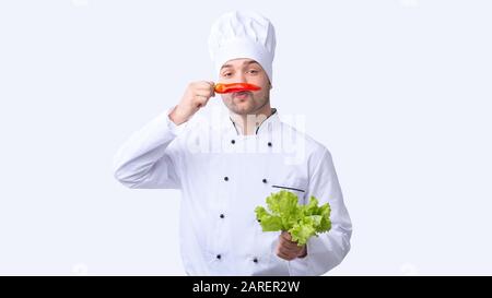 Lustiger Chef Mann Hält Red Pepper Wie Schnurrbart, Studio Shot Stockfoto