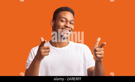 Aufgeregter schwarzer Kerl, der Sie über orangefarbenem Hintergrund wählt Stockfoto