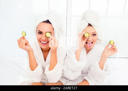 Komische junge Schwestern nach dem Duschen Maske mit Gurke Stockfoto