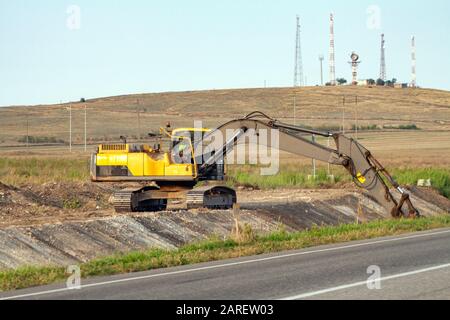 Einem großen eisernen Baggerschaufel sammelt und schüttet Sand Geröll und Steinen in einem Steinbruch auf der Baustelle Straße Einrichtungen und Häuser Stockfoto