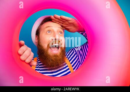 Nahaufnahme aufgeregt lustiger Mann zusehen rosafarbenes Leben Relax Saver Rettung Blick nach vorne Schrei ome tragen weiße Sonnenhut orange Hosenträger nautische Weste Stockfoto