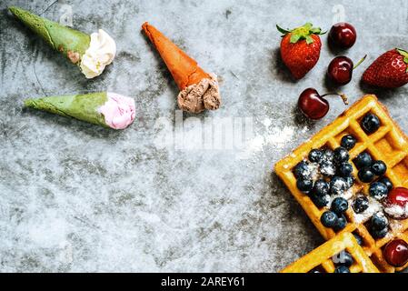 Eis und Waffeln mit leckeren roten Früchte voller gesunder Vitamine, über dunklen Stein Hintergrund mit Kopie Platz für Text. Stockfoto