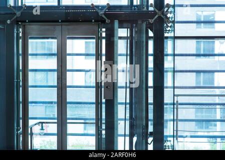 Glasaufzug, Geschäftsmann mit modernem Glasaufzug in die oberen Etagen, hohes Gebäude, Büro- und Einkaufszentrum und Hotel, Transport Stockfoto