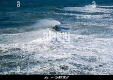 Große Surfwellen brechen in der Nähe des Strandes in Praia do Norte in Nazare, Portugal Stockfoto