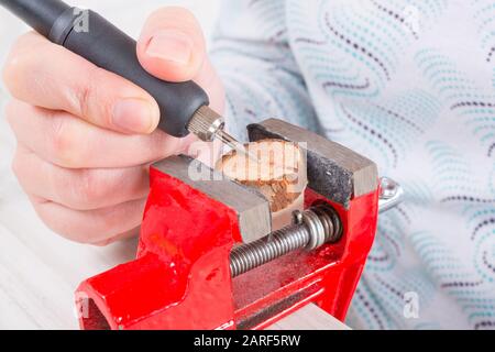 Frau, die ein schnelles Drehwerkzeug verwendet, um Schmuck auf einer Holzscheibe zu gravieren Stockfoto