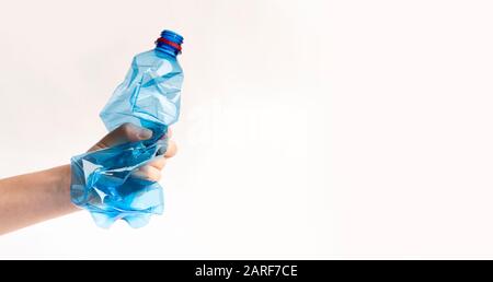 Weibliche Hand, die Zerknitterte oder gestürzte Plastikflasche hält Stockfoto