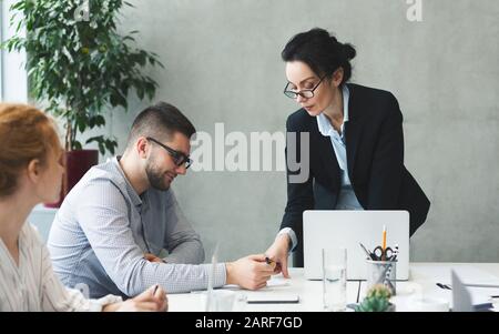 Geschäftsfrau zeigt und erklärt dem Partner Geschäftsdokumente Stockfoto