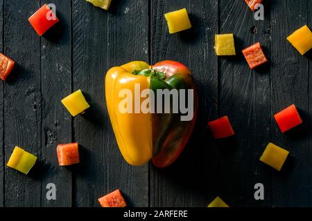 Rote Und gelbe Peppers Auf schwarzer Holzoberfläche Geschnitten Stockfoto