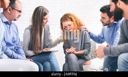 Unterstützen Sie Gruppenmitglieder, die depressive Frauen bei einer Psychotherapiesitzung trösten Stockfoto