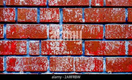 Bunte Ziegelwand mit gerissener rötlicher Farbe und blauen Gelenken, dunkler Loft-Hintergrund Stockfoto