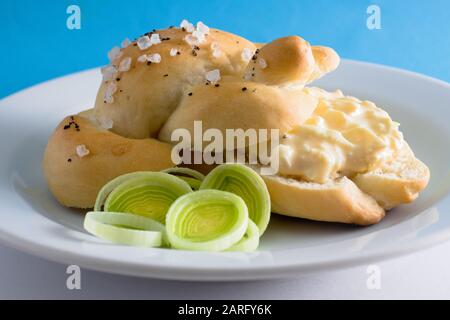 Hausgemachter Brötchen mit Eierspreizung auf einer weißen Platte mit grünem Lauch Stockfoto