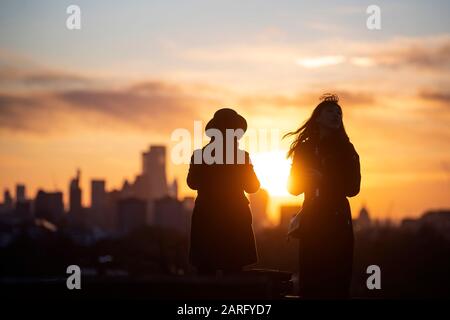 Die Menschen auf dem Primrose Hill beobachten den Sonnenaufgang über London. Stockfoto